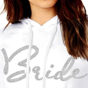 May include: White hoodie with the word "Bride" spelled out in rhinestones.