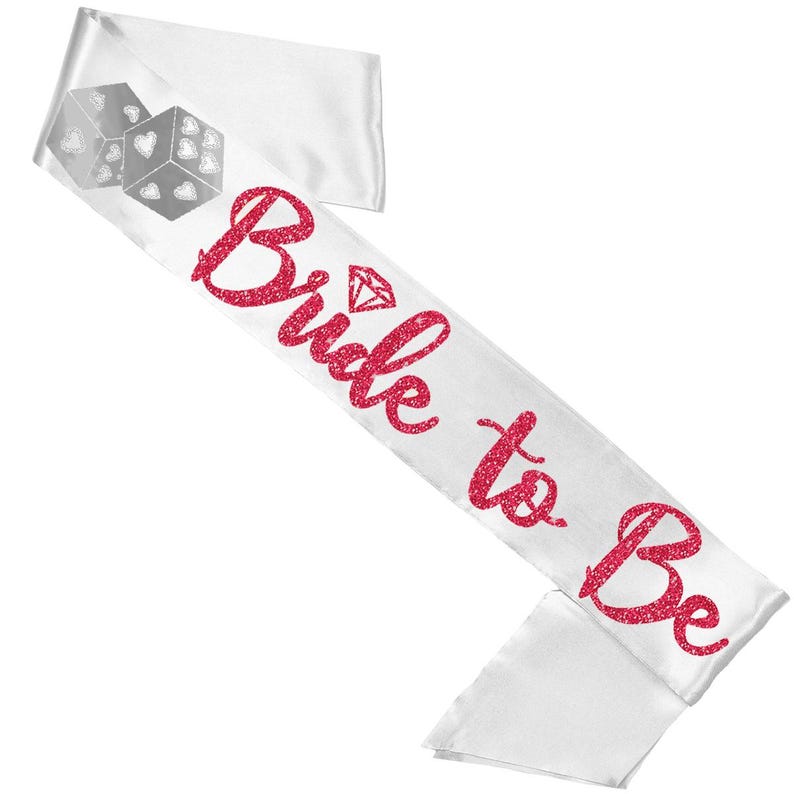 以下が含まれることがあります： 赤いグリッターのスクリプトで「Bride to Be」の文字が入った白いサテンサッシュ。サッシュにはダイヤモンドのグラフィックとハートのシンボルが付いた2つのサイコロが付いています。ブライダルシャワーや独身最後のパーティーに最適なアクセサリーです。