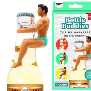 Puede incluir: Una botella de cerveza con tapa plateada y una figura de un hombre en ba&ntilde;ador turquesa sentado encima. El embalaje dice "Bottle Buddies Drink Markers" e incluye el texto "Clay, Dom, Tom & Trey".