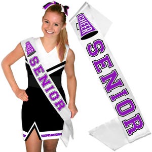 May include: A white satin sash featuring the word SENIOR in bold purple block letters with a black outline, accompanied by a purple megaphone graphic. The sash is displayed both on a cheerleader wearing a black and white uniform and separately.