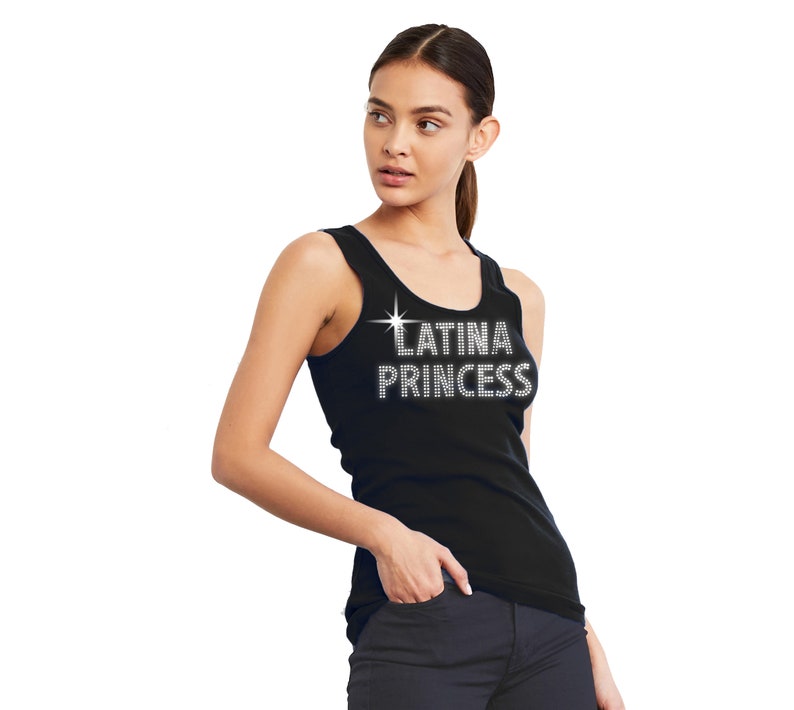 May include: A black sleeveless tank top featuring the text LATINA PRINCESS in a silver-toned, rhinestone-style font across the chest, accompanied by a small four-pointed star graphic positioned above the first letter of the word LATINA.