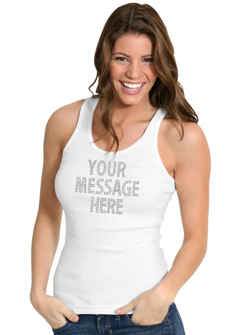 May include: A white ribbed tank top featuring the text YOUR MESSAGE HERE spelled out in small, silver-toned metallic studs across the chest. The garment has a scoop neckline and a fitted silhouette, providing a clean and simple aesthetic.