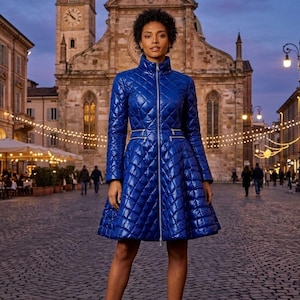 Può includere: Un cappotto trapuntato di un vivace blu reale con collo alto, cerniera frontale argentata a tutta lunghezza e due tasche orizzontali con cerniera in vita. Il cappotto ha un corpetto aderente che si allarga in un orlo svasato sopra le ginocchia.