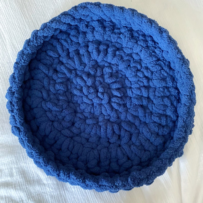 May include: A blue crocheted pet bed with a round shape and a textured surface.