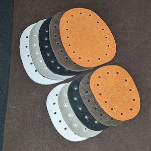May include: A set of 10 leather patches in various shades of brown, grey, and black. The patches are oval-shaped and have a circle of evenly spaced holes around the edge.
