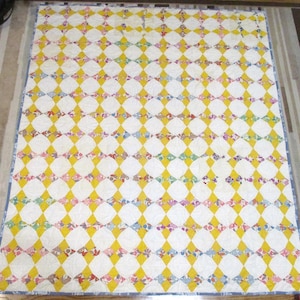 May include: A vintage quilt with a diamond pattern in yellow, white, and various shades of pink, blue, and green.