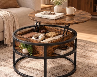 May include: A round coffee table with a dark wood grain finish and a black metal frame. The top lifts to reveal a hidden storage compartment containing headphones and small items. A lower shelf holds a small potted plant and stacked books.