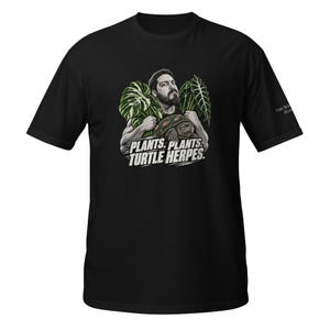 May include: A black short-sleeve t-shirt featuring a graphic of a person holding large green leaves and a turtle. Below the illustration, the text reads: PLANTS. PLANTS. TURTLE HERPES. The sleeve features small white text that reads THE ROOTS PLANTS.