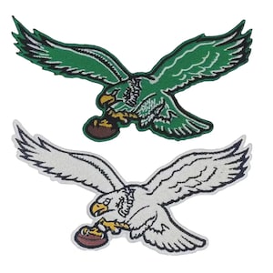 May include: Two embroidered fabric patches featuring an eagle in flight with wings spread wide. The top patch is green with white and black details, while the bottom patch is white with black and yellow details. Both eagles are clutching a football.