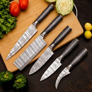 May include: A set of five kitchen knives with patterned Damascus steel blades and dark, wood-grain textured handles. The collection includes a chef knife, a rectangular cleaver, a utility knife, a paring knife, and a curved bird's beak knife.