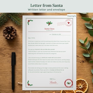 Puede incluir: Una carta blanca de Santa Claus con bordes de acebo rojos y verdes, que incluye el texto Dear Emma, fechada el 24 de diciembre de 2026 y firmada por Santa. El documento presenta un sello circular rojo y un encabezado del Polo Norte.