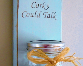 May include: A light blue wooden sign with the text "If These Corks Could Talk" in a decorative font. A glass jar with a metal lid and a brown raffia bow is attached to the sign.
