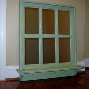 May include: A green painted wooden window frame mirror with a shelf and hooks underneath. The mirror is divided into nine panes.
