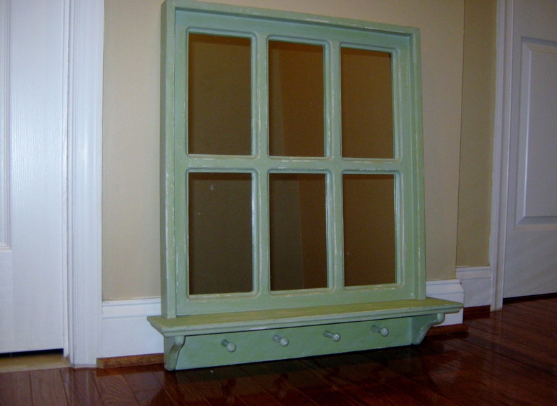 May include: A green painted wooden window frame mirror with a shelf and hooks underneath. The mirror is divided into nine panes.