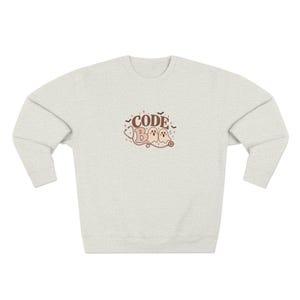 May include: A light heather gray crewneck sweatshirt featuring a central graphic with the text CODE BOO in brown and pink. The design includes two ghost illustrations, a stethoscope outline, small stars, and bats in brown and pink tones.