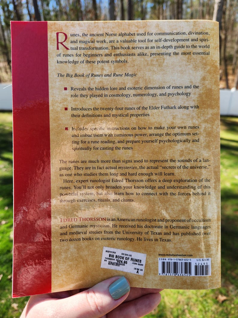 Op de afbeelding: De achterkant van een boek getiteld "The Big Book of Runes and Rune Magic" door Edred Thorsson. De boekomslag is bruin met rode tekst en een rode rand. De boekomslag bevat een beschrijving van de inhoud van het boek en de biografie van de auteur. De boekomslag bevat ook een barcode en een ISBN-nummer.