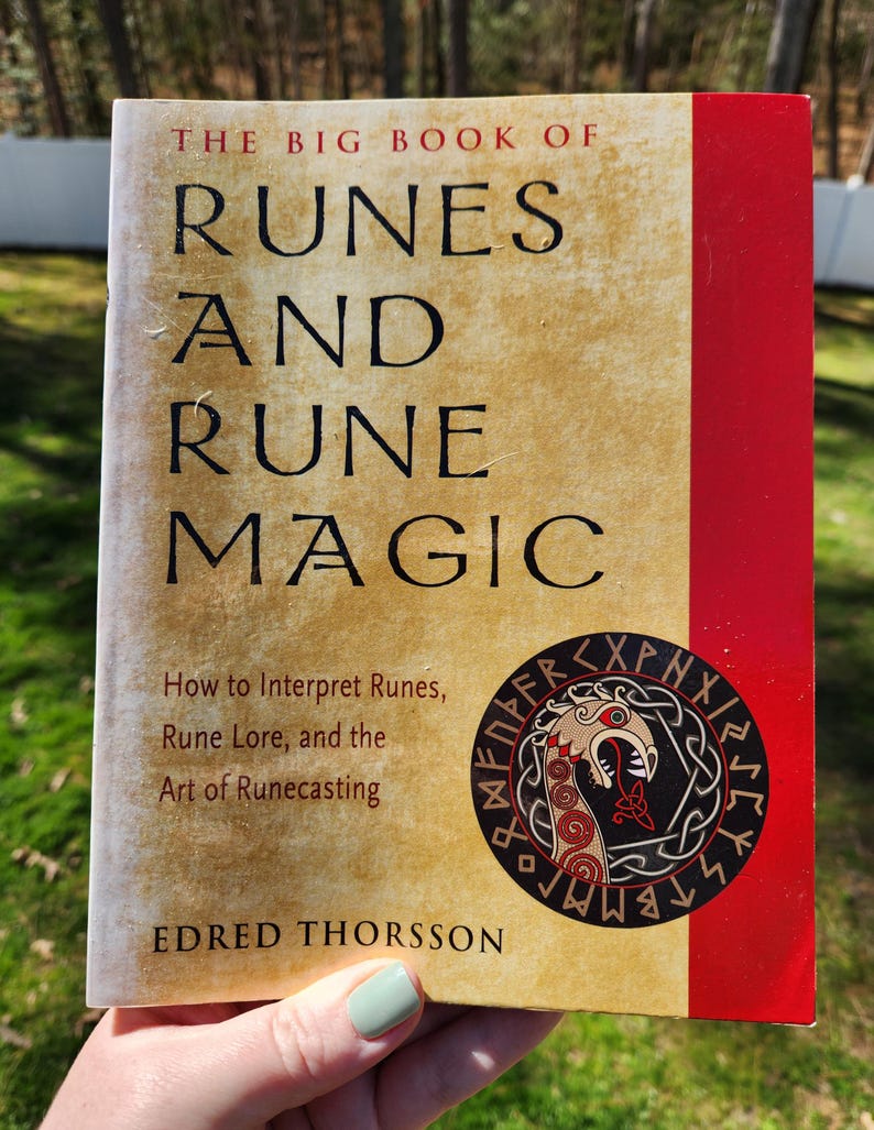 Op de afbeelding: Het Grote Boek van Runen en Runenmagie door Edred Thorsson. De omslag van het boek heeft een rood en gouden ontwerp met een zwart-witte illustratie van een drakenkop omringd door runen.