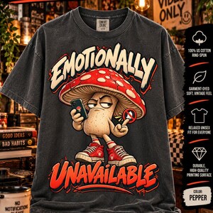 Może przedstawiać: Antracytowy t-shirt unisex Comfort Colors 1717 barwiony w masie z grafiką grzyba trzymającego smartfon z napisem Emotionally Unavailable. Grzyb ma na sobie czerwone trampki oraz czerwono-biały kapelusz.
