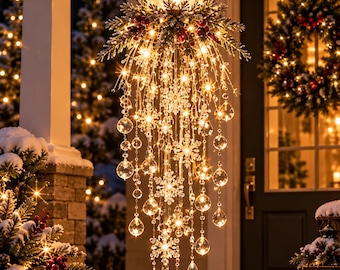 May include: A hanging light fixture featuring a large crackle glass sphere at the top, adorned with pine branches and red berries. Cascading strands of warm white LED lights, clear crystal spheres, and snowflake ornaments hang downward.