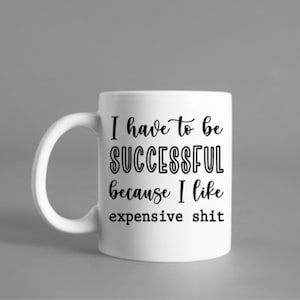 May include: White ceramic mug with a curved handle. The mug features black text that reads "I have to be SUCCESSFUL because I like expensive shit."