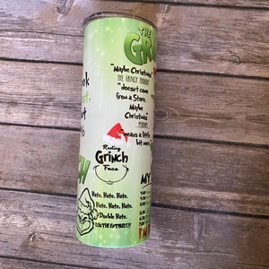 May include: A green and white tumbler featuring the Grinch. The tumbler has text that reads "Maybe Christmas doesn't come from a store" and "Resting Grinch Face." The tumbler also has a schedule printed on it.