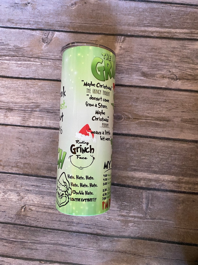 May include: A green and white tumbler featuring the Grinch. The tumbler has text that reads "Maybe Christmas doesn't come from a store" and "Resting Grinch Face." The tumbler also has a schedule printed on it.