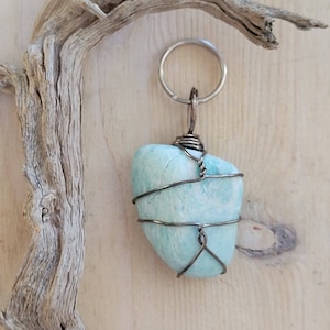 May include: A light blue stone wrapped in silver wire, attached to a silver key ring. The stone is a natural, irregular shape and has a smooth, polished surface.