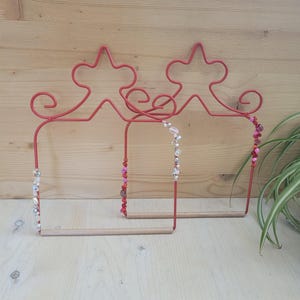 May include: Three red metal bird perches with wooden dowels and colourful beaded decorations. The perches are shaped like a crown with a decorative top.