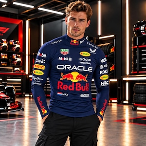 May include: A dark blue long-sleeve mock neck shirt featuring various sponsor logos including Oracle, Red Bull, Mobil 1, and Tag Heuer. The chest displays a large Red Bull graphic with two red bulls and the text Max with a Dutch flag.