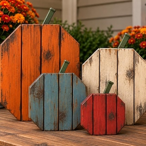 May include: A set of four octagonal pumpkin decorations made from vertical wooden planks with a distressed finish. The pumpkins are painted in orange, blue, cream, and red, each featuring a small green metal stem attached to the top edge.