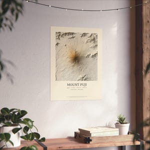 May include: A cream-colored wall art print featuring a topographic relief map of Mount Fuji. The text reads MOUNT FUJI, Japan, 35.3606 N, 138.7274 E, State of Shizuoka, Yamanashi. The map displays detailed terrain shading in shades of beige and brown.