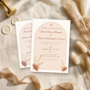 May include: A wedding invitation card featuring an arched design in soft peach tones. The text reads: Together with their families, Olivia Grace Bennett and James Alexander Carter, request the pleasure of your company at the celebration of their marriage.