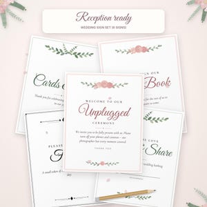 May include: A wedding sign set featuring eight white cards with pink floral accents and green leaves. The central sign reads: Welcome to our Unplugged Ceremony. We invite you to be fully present with us. Please turn off your phones and cameras.