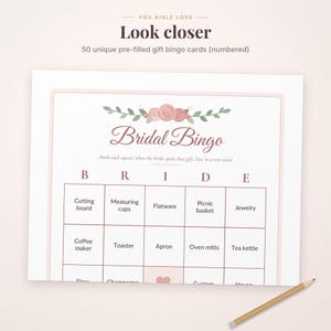 May include: A white Bridal Bingo game card featuring a floral header with pink roses and green leaves. The text reads Bridal Bingo, Mark each square when the bride opens that gift, Five in a row wins!, and lists items like Cutting board, Measuring cups, Flatware, Picnic basket, Jewelry, Coffee maker, Toaster, Apron, Oven mitts, and Tea kettle.