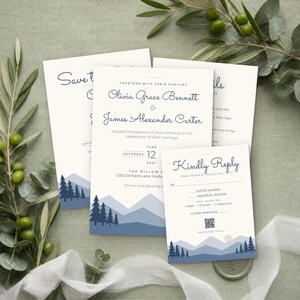 May include: A wedding invitation suite featuring cream-colored paper with dark blue text and a mountain landscape graphic at the bottom. The cards include names Olivia Grace Bennett and James Alexander Carter, a date of June 12, 2027, and a QR code.