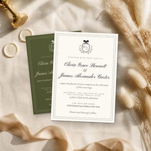 K&ouml;nnte beinhalten: Eine cremefarbene Hochzeitseinladungskarte mit schwarzem Text und einem kleinen Schleifensymbol &uuml;ber den Initialen O/J, mit einem gewellten Rand. Eine zweite, identische Einladung in Olivgr&uuml;n liegt unter der cremefarbenen Karte.
