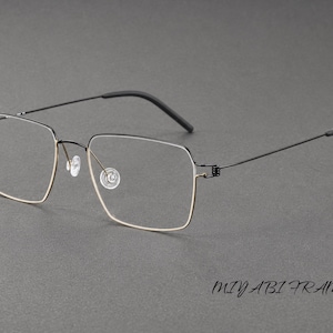 Puede incluir: Gafas con una montura fina de metal negro de forma cuadrada y bordes inferiores en tono dorado. Las varillas son de metal negro delgado con puntas oscuras y las almohadillas nasales son transparentes. El texto MIYABI FRAME aparece abajo.