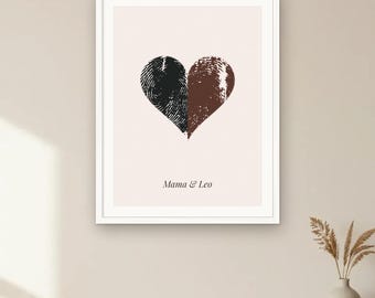 May include: A framed wall art print featuring a heart shape composed of two distinct fingerprints, one black and one brown, on a light cream background. Below the heart, the text Mama & Leo is printed in a simple, dark serif font.
