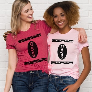 May include: Two people wearing t-shirts with a crayon design. The shirts are pink and red with black crayon outlines and the word "Crayon" written inside the crayon.