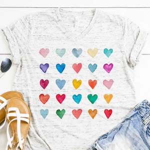 May include: A white t-shirt with a v-neck and a pattern of colourful watercolour hearts.