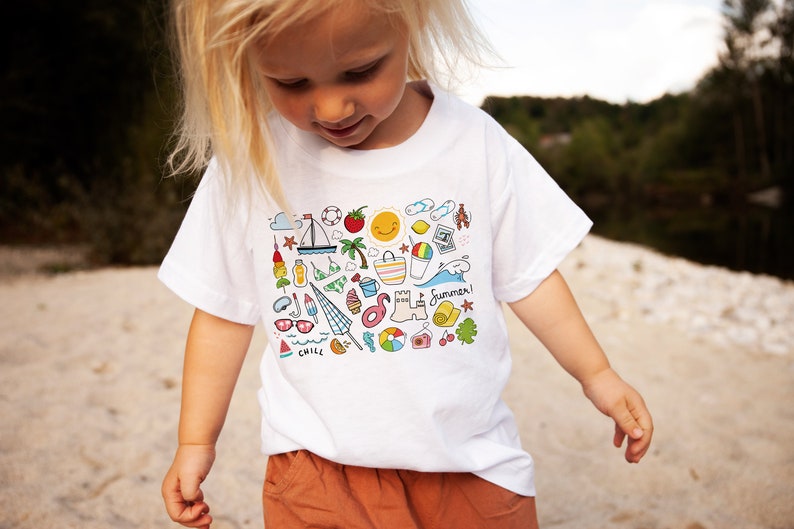 Op de afbeelding: Een wit T-shirt met een kleurrijk zomerthema-ontwerp met verschillende pictogrammen zoals een zeilboot, een parasol, een ijsje, een watermeloen en een zonnebril. De tekst "Summer!" is op het shirt gedrukt.