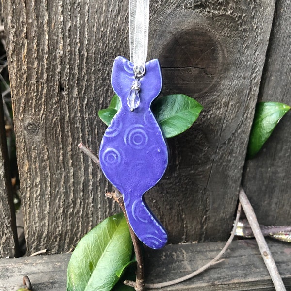 handcrafted charming sitting cat ornament, glazed in regal purple, adorned with white ribbon, sparkling faceted glass bead, artisan elegance