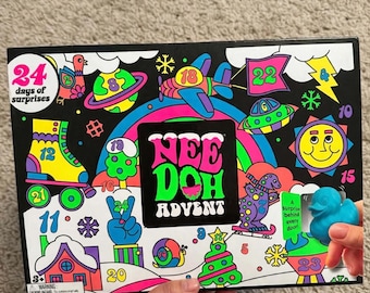 May include: A Nee Doh Advent calendar box with a black background featuring colorful illustrations of a roller skate, airplane, sun, and snail. The text reads 24 days of surprises and Nee Doh Advent. A blue rubber duck toy is attached to the front.