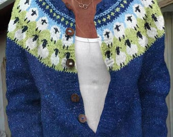 May include: A blue knit cardigan featuring a yoke pattern of white sheep with black details against a light green background. The garment has long sleeves, a round neckline, and a front button closure with five brown circular buttons.
