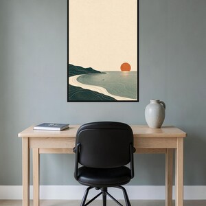 Puede incluir: Una l&aacute;mina de arte mural enmarcada que muestra un paisaje costero minimalista con una costa verde oscuro, una playa de arena beige claro, agua azul gris&aacute;cea tranquila y un gran sol naranja s&oacute;lido centrado en un cielo crema p&aacute;lido.