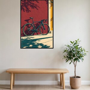 Op de afbeelding: Een donkergekleurde racefiets met dunne banden en een racestuur staat geparkeerd tegen een felrode muur naast een geel deurkozijn. De sc&egrave;ne toont scherpe schaduwen die door de fiets en het nabijgelegen gebladerte op de grond vallen.