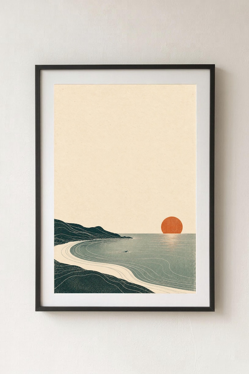Puede incluir: Una impresi&oacute;n de arte mural enmarcada que muestra un paisaje costero con una costa verde oscuro, una playa de arena beige claro y agua azul gris&aacute;cea tranquila. Un gran sol naranja s&oacute;lido se asienta en el horizonte bajo un cielo crema.