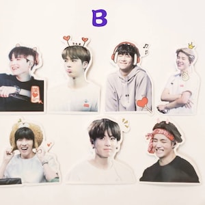 May include: Set of seven stickers featuring different members of a K-pop group. Each sticker has a white background and features a close-up photo of a person with a cartoon-like accessory on their head. The stickers are printed with high-quality images and are perfect for decorating laptops, water bottles, and other personal items.