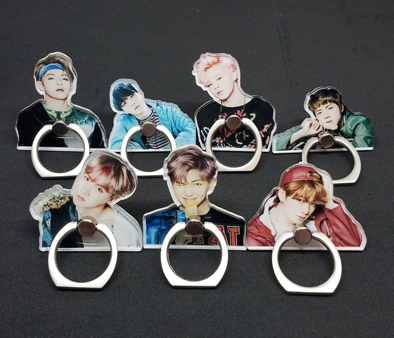 May include: Seven colorful phone ring holders with different images of people. Each holder has a silver ring.