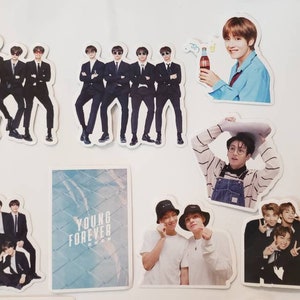 May include: A collection of stickers featuring a K-pop boy band. The stickers are printed on white paper and feature various images of the band members, including a group photo, individual portraits, and a photo of the band members holding a Coca-Cola bottle. The stickers also feature the text "Young Forever".